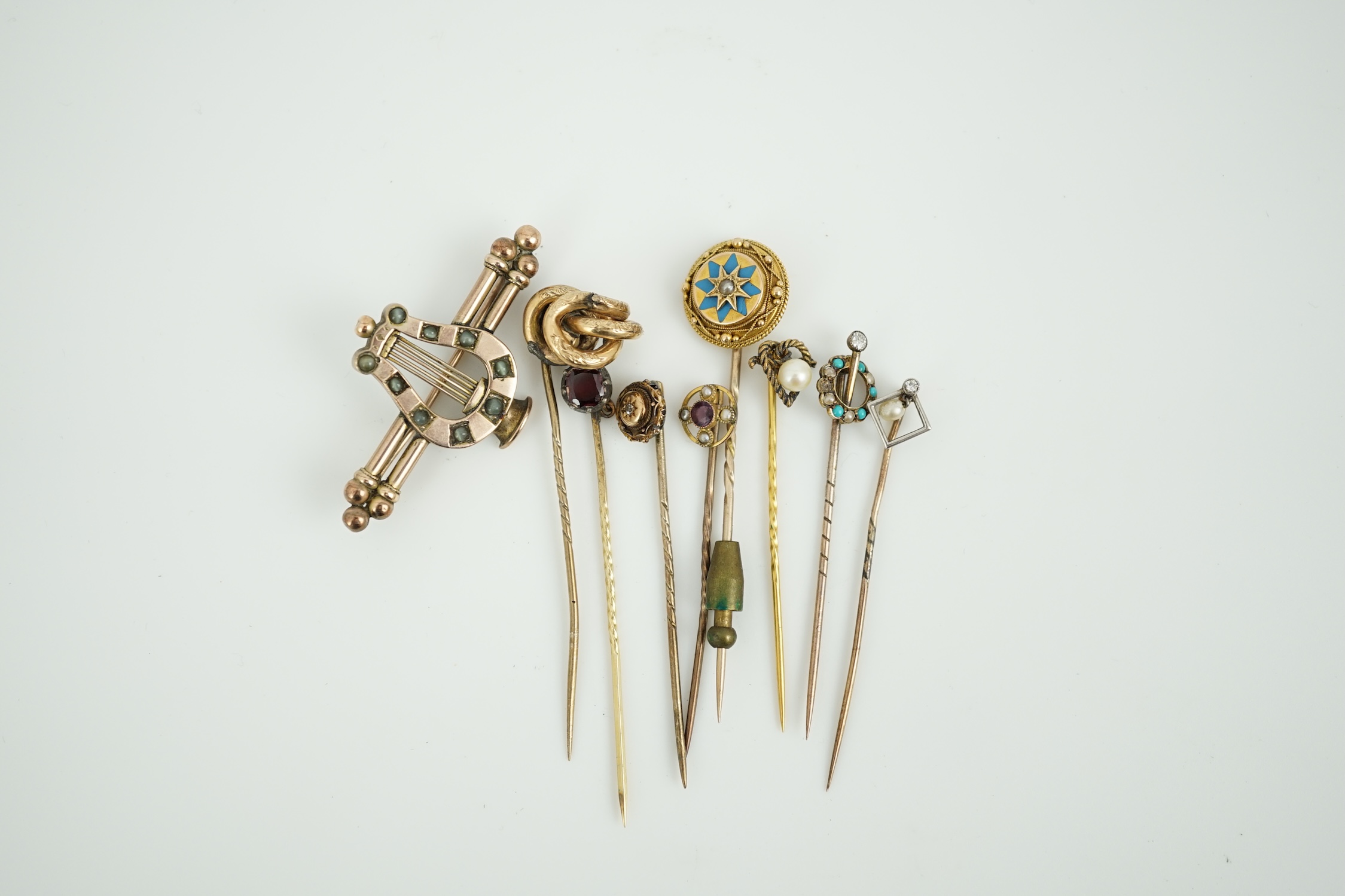 A Victorian yellow metal and cat's eye chrysoberyl set lyre bar brooch, 51mm and eight assorted gem set yellow metal stick pins including enamel and diamond set.